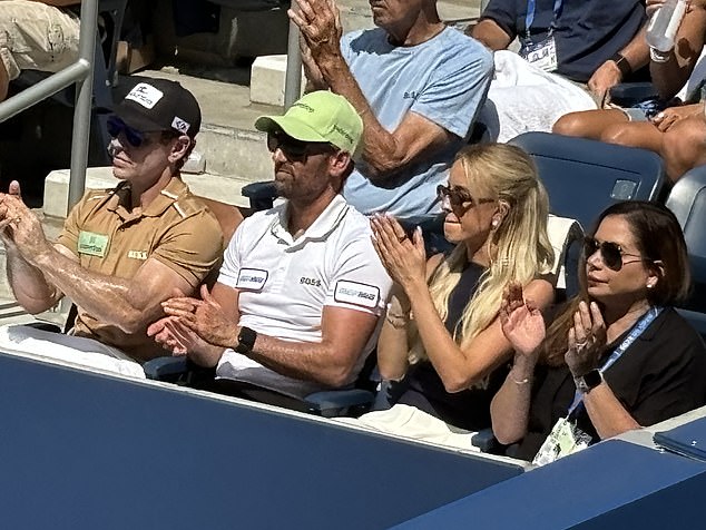 Model Riddle applauds her man from the front row despite the scorching sun in New York City