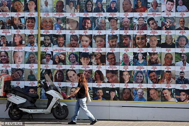 A person walks past a wall displaying posters of hostages, most of whom were kidnapped during the deadly Oct. 7 attack by Hamas, in Tel Aviv, Israel.