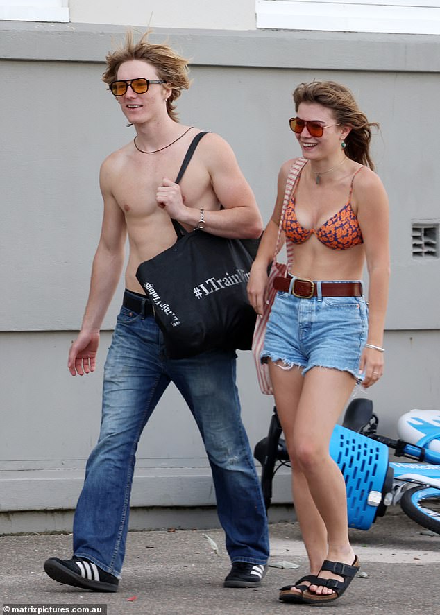 In keeping with the old-school style, Mia paired her swimsuit with a pair of high-waisted denim shorts, a brown belt and red-tinted sunglasses.