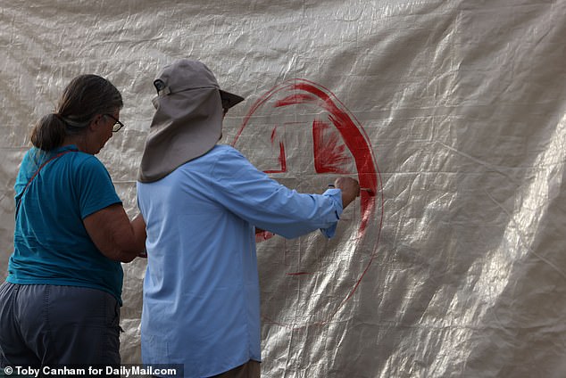 Aid workers paint a tent with a red cross on the hole in the border wall east of Sasabe