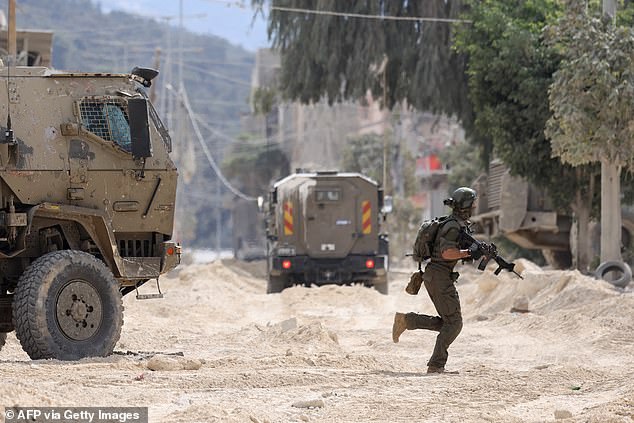 An Israeli soldier is seen near armoured vehicles during a raid at the Nur Shams refugee camp.