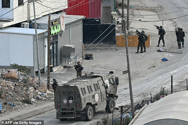 Israeli soldiers walk down a street during a raid on al-Faraa camp near the city of Tubas