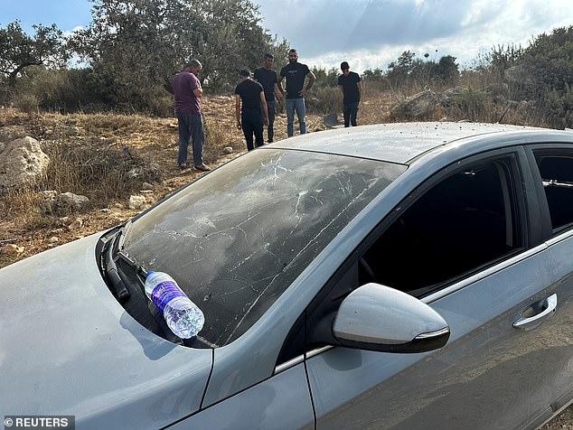 Palestinians assess the damage to a car during a military operation by Israeli forces near Jenin, in the Israeli-occupied West Bank.