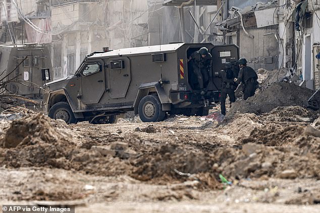 Israeli soldiers disembark from an armored vehicle as they take up position during an army operation in Tulkarem