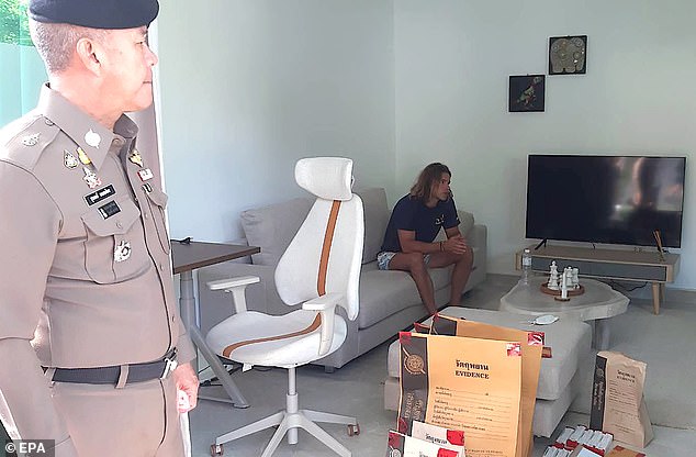 A photograph provided by the Royal Thai Police shows Spanish chef Bronchalo sitting next to evidence and a police officer, after he was arrested for murder and dismembering the body of a Colombian man.