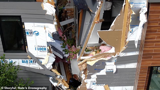 The extraordinary sight shows furniture scattered across the front of the house, a mattress hanging precariously from the second floor and parts of the house's structure dangling in the rubble.