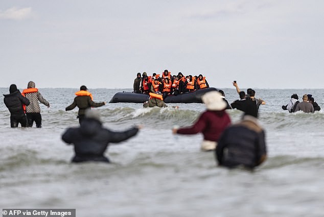 Migrants wade through the water as they desperately try to board a smuggler's boat off the northern coast of France (file image)