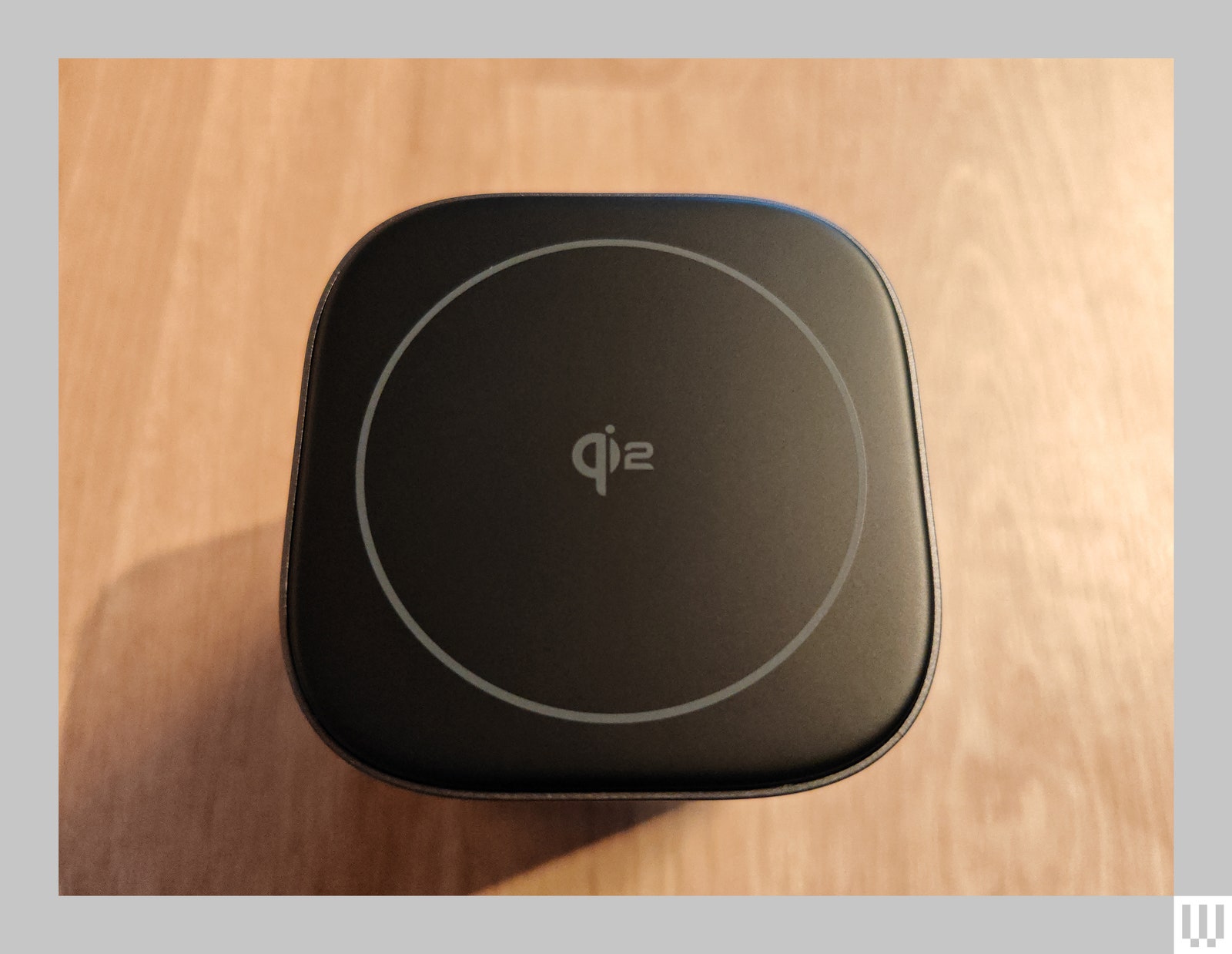 Overhead view of a black square charger on a wooden surface