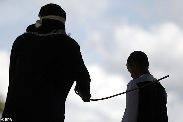 A baton hits a prisoner's back as he is being whipped in Aceh province, Indonesia