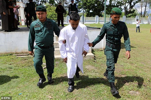 Sharia police lead a prisoner to receive his punishment after he was reportedly caught gambling, which is illegal under Sharia law