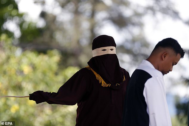 An executioner known as 'algojo' carries out a public flogging in the town of Jantho, Aceh