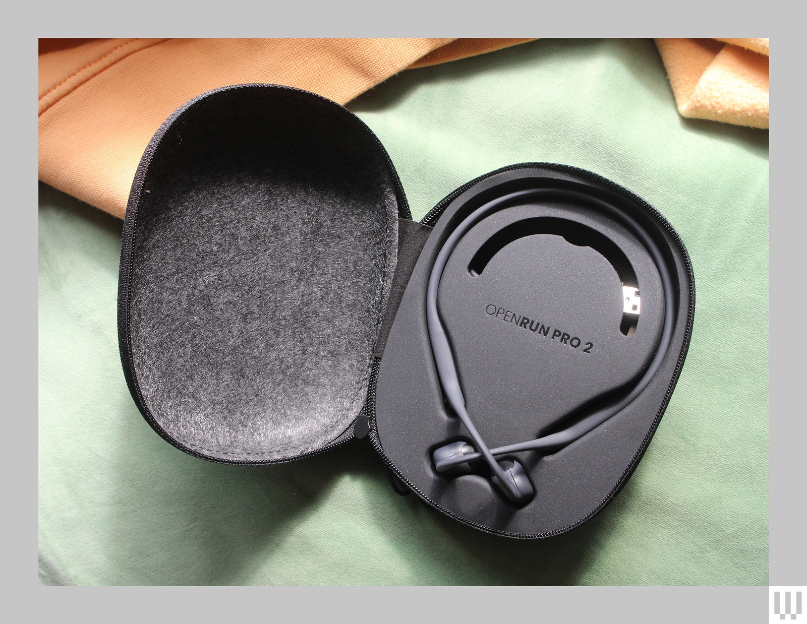 A black clamshell-style case containing thin headphones that wrap around the back of your head.