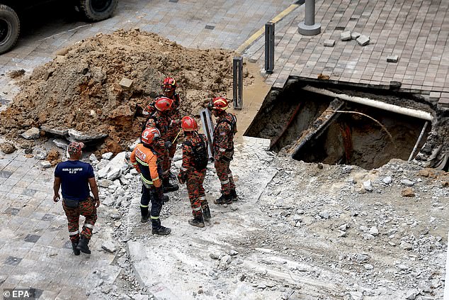 Malaysian Fire and Rescue Department officials inspect the site where a woman fell into an eight-metre-deep sinkhole