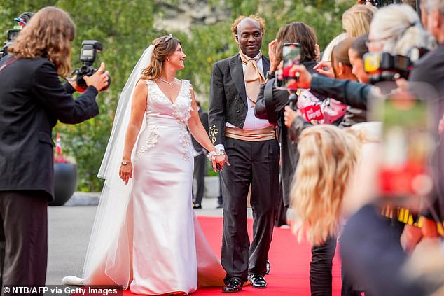 The happy couple hold hands as they walk the red carpet in front of press and a crowd of fans.