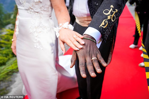 Showing off their wedding rings and intricate detailing on both outfits.