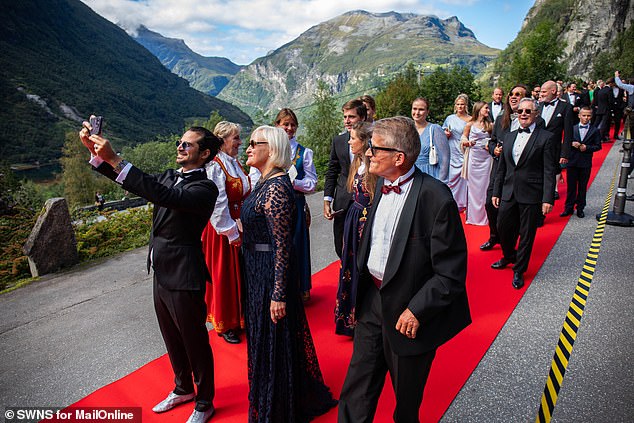 More guests walking the red carpet and taking selfies against the beautiful backdrop.