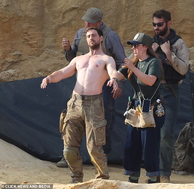 Taylor-Johnson on the set of Fuze shirtless and in beige pants