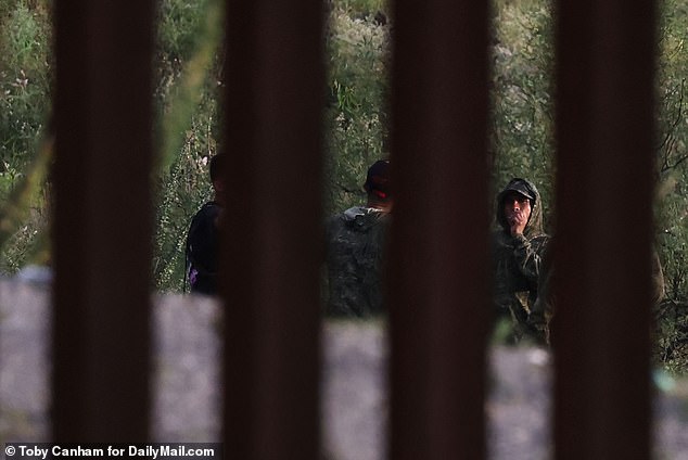 They were joined by a group of migrants who appeared to have installed a cross right in the gaping hole in the wall.