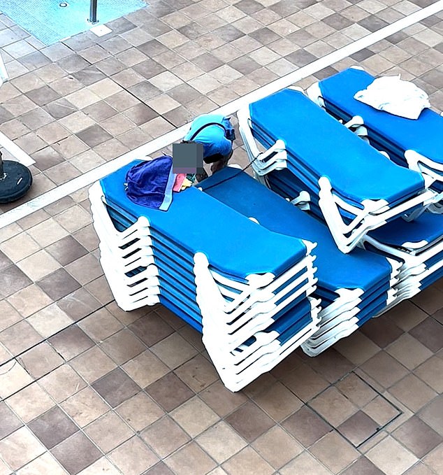 A man appears to remove secured sun loungers in an attempt to get the best spot by the pool.