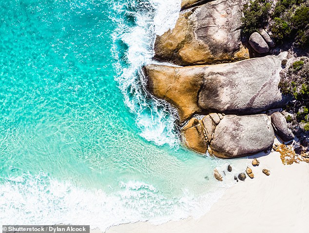 Iconic giant rocks sit atop pristine white sands next to water so blue it's 