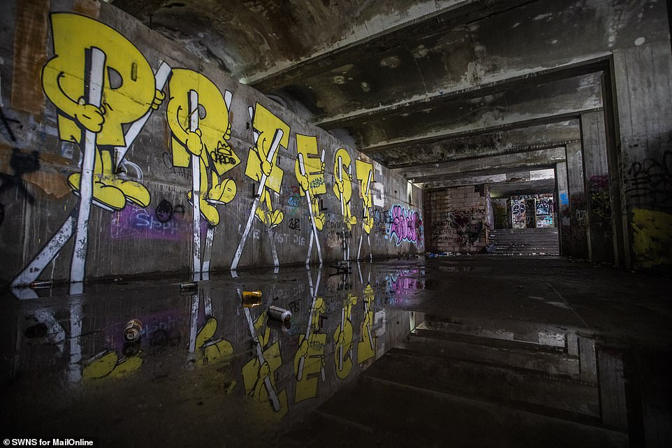 A nod to his past, Priest is emblazoned on the wall in bright yellow writing, reflecting off the gloomy, flooded floor.