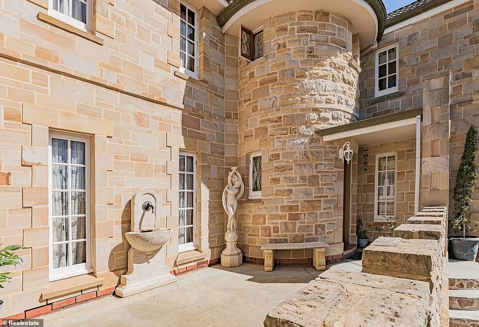 The grand entrance features stairs leading to a welcoming terrace up to the gently curved Naytoah wooden entrance door with statues and a fountain to the side.