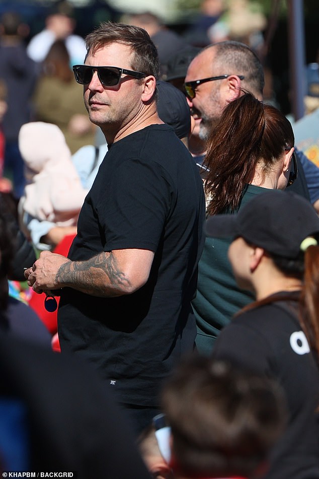 The father-of-one opted for a dark monochrome look in a black T-shirt and shorts while shielding his eyes from the sun with sunglasses.