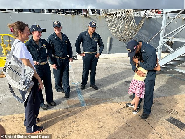 A 7-year-old girl hugs a Navy sailor at Joint Base Pearl Harbor-Hickam in Honolulu on Aug. 28, 2024. The Navy ship launched a small crew to rescue the girl, her mother, her cat and her turtle after their sailboat became beset by weather in the path of an approaching hurricane.