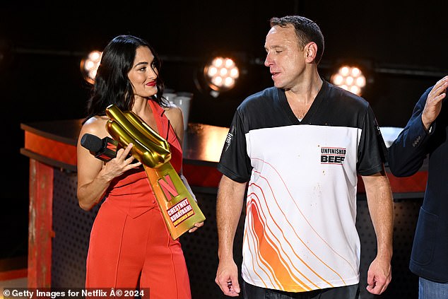 Nikki beamed as she held up the comical hot dog-shaped trophy alongside winner Joey Chestnut.