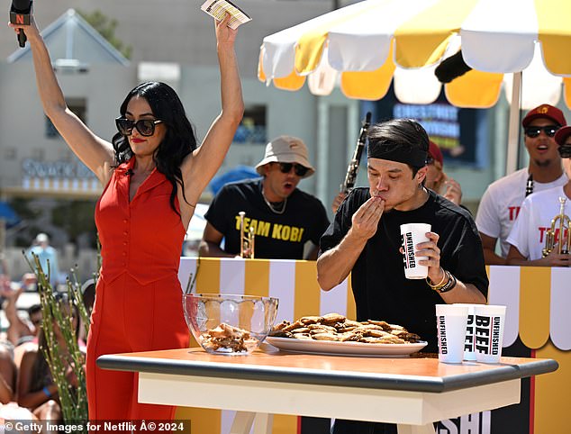 The WWE pro looked jubilant in a bright red sleeveless bodysuit with her jet-black hair cascading in loose waves.