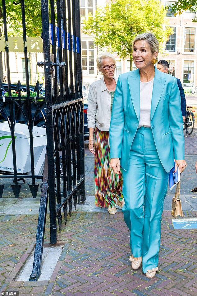 She opted for beige accessories, including a bag with a gold clasp and heels decorated with bows.