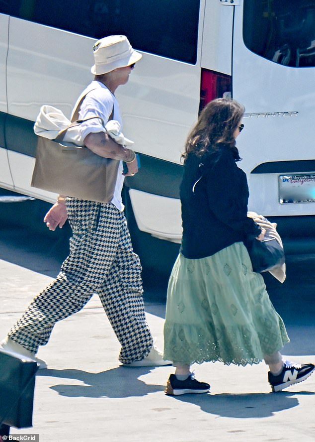 The 60-year-old Hollywood actor sported a pair of baggy houndstooth trousers paired with a white bucket hat and a brown handbag as he walked to his vehicle after his long drive home.