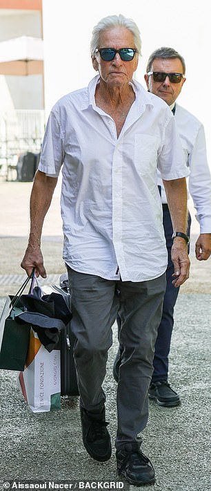 Michael Douglas looked dapper as ever in a white shirt and grey trousers.