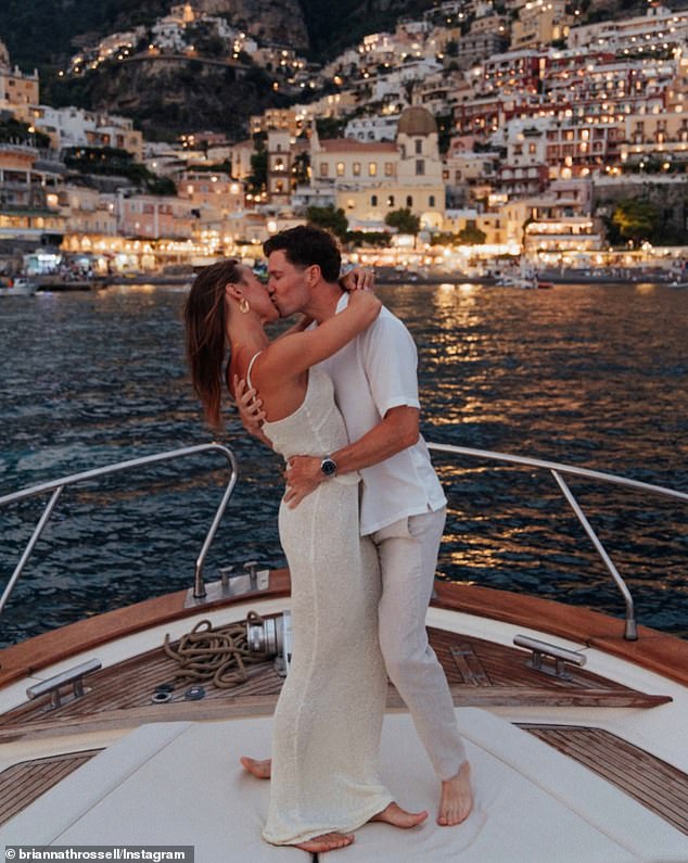 In a second image, the genetically blessed couple celebrate the moment by sharing a tender embrace, with the lights of Positano shining in the distance.