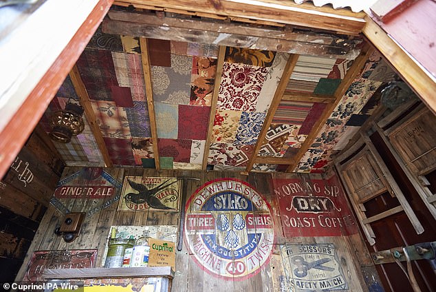 The walls are decorated with brightly coloured vintage posters, while the ceiling appears to be a mosaic of patterned papers.