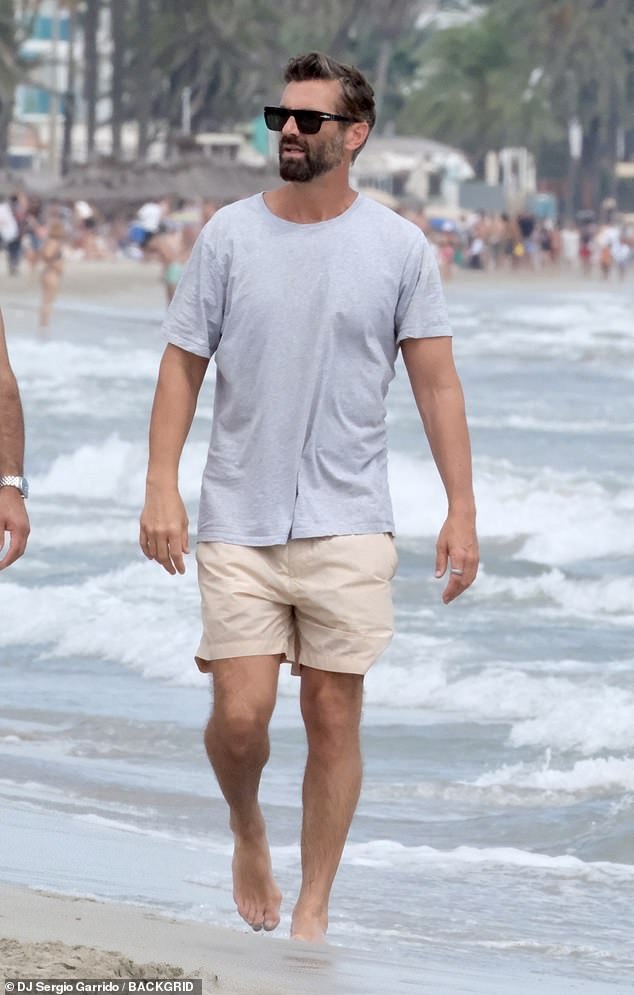 Meanwhile, Chris was spotted strolling along the beach in a pair of dark sunglasses, a grey T-shirt and cream chino shorts.