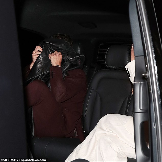 He held a coat in front of his face while Florence sat next to him.