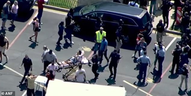 Pictured: An injured victim receives help from emergency services following the shooting.