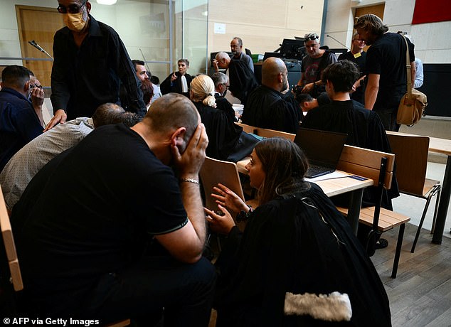 Some of the 50 co-defendants accused of rape speak to a lawyer in court in the case that has shocked France on Monday