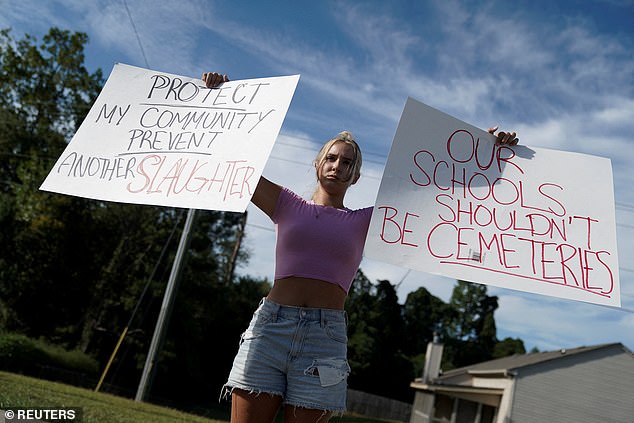 Student Gretchen Gierlach, 18, holds signs after a shooting at Apalachee High School in Winder