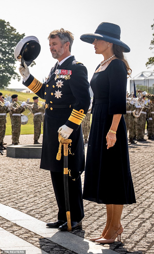 King Frederick is pictured removing his hat as he takes part in the wreath-laying ceremony with Mary.