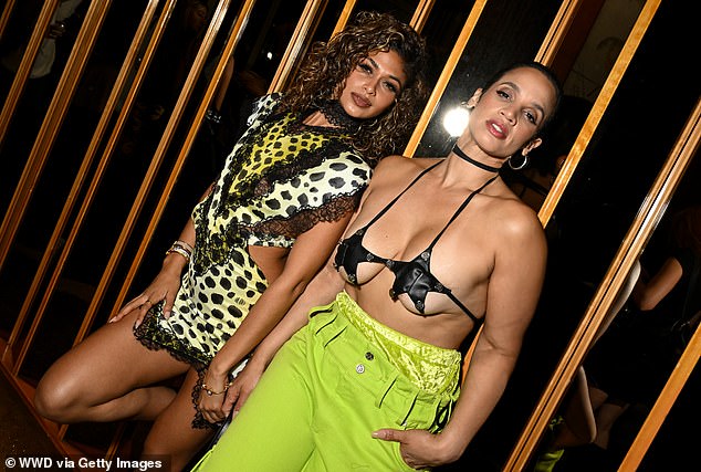 She accessorized with a black choker and large solid silver hoop earrings and posed next to her friend, who held her fingers.