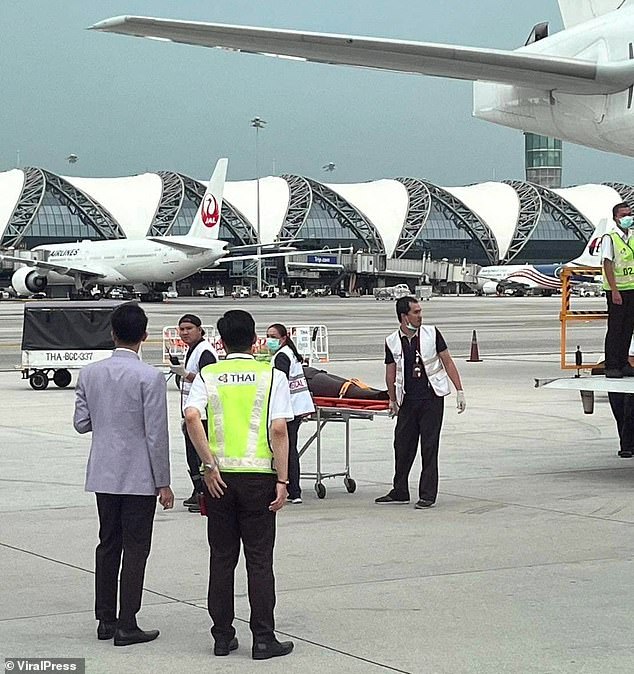 A person is seen being taken off the plane on a stretcher on May 20 in Bangkok.