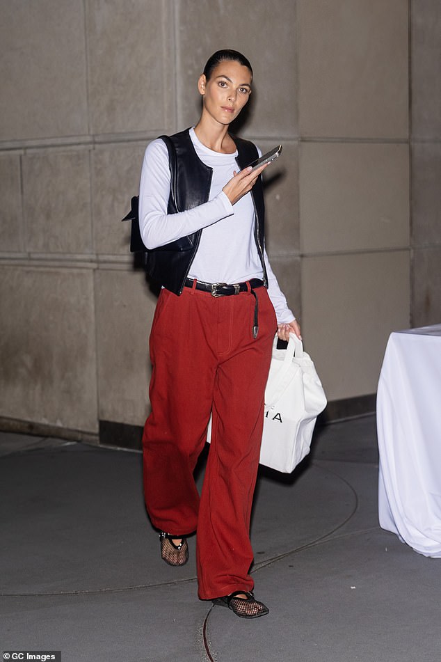 The Italian beauty opted for a relaxed look in a white top, a black leather vest and bright red oversized trousers.