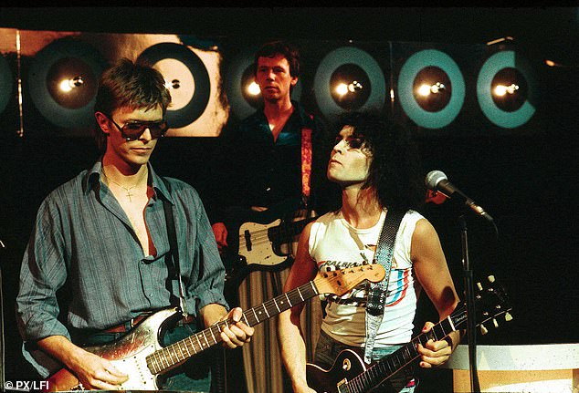 Flowers appears in the background as he performs alongside legends David Bowie and Marc Bolan.