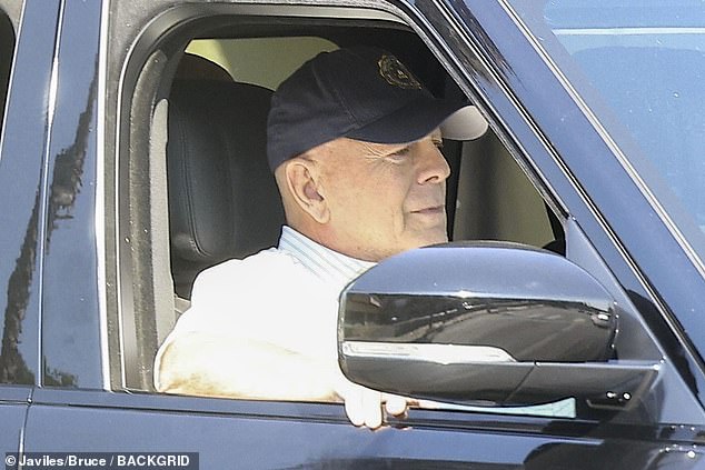 The Pulp Fiction actor sat in the passenger seat of a vehicle wearing a black baseball cap and a collared button-down shirt with horizontal gray stripes.