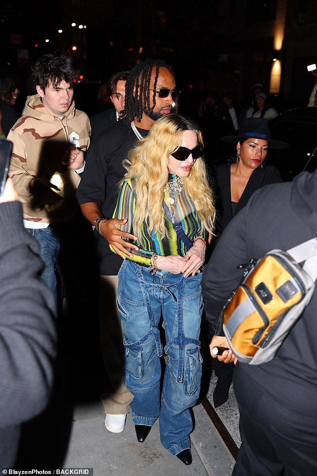 Both she and her boyfriend wore sunglasses as they walked around the party hand in hand.