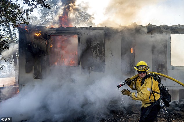 Firefighter Gus Laws extinguishes flames at a home as the Boyles Fire burns in Clearlake, California, Sunday, Sept. 8.