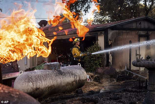 Firefighter Nolan Graham sprays water around a burned garage as the Boyles Fire burns in Clearlake, California, Sunday, Sept. 8.