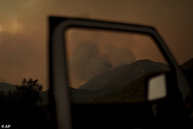 Smoke and flames from the advancing Line Fire rise above a ridge.